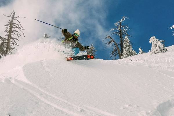 a skier coming downhill in powder spraying snow